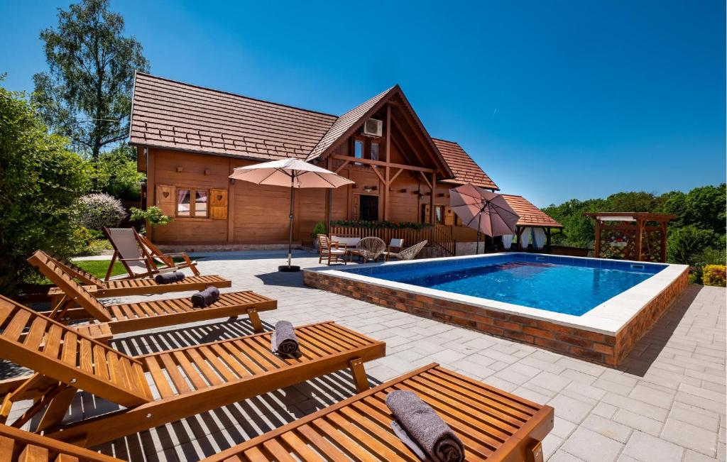 une piscine avec des bancs en bois et une maison dans l'établissement Four-Bedroom Holiday Home In Velika Buna, à Velika Buna
