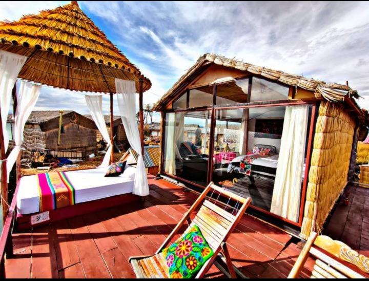 プーノにあるTiticaca uros floating lodgeのガゼボのあるデッキにベッドと椅子が置かれている