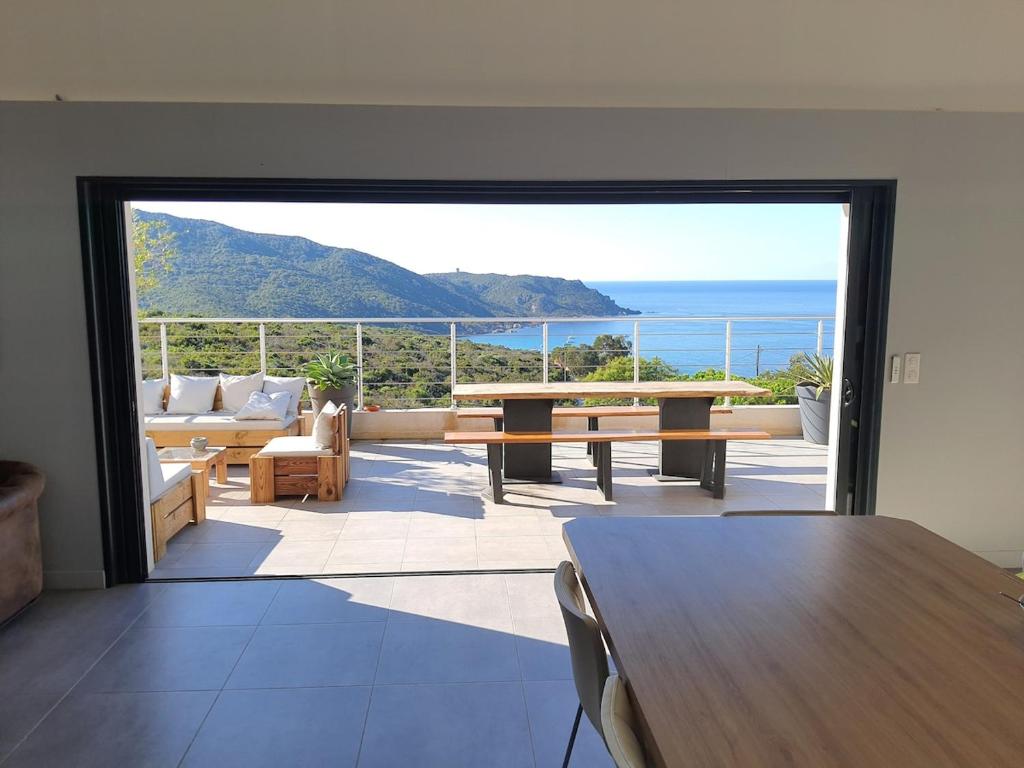 - un salon avec une table et une vue sur l'océan dans l'établissement Superbe villa moderne sur Capo di Muro, à Coti-Chiavari