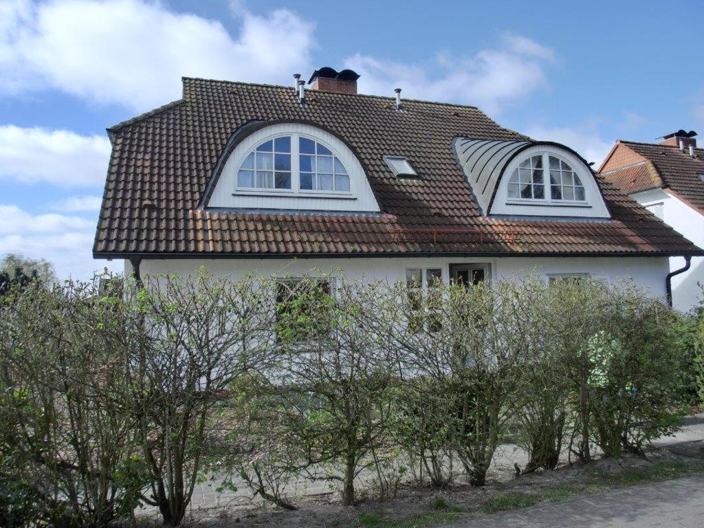 una casa blanca con techo marrón y algunos árboles en Achterwasserblick, en Zempin