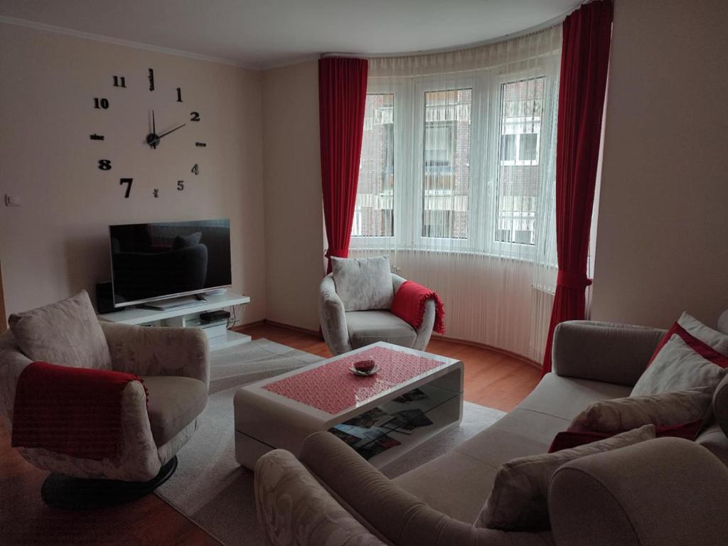 a living room with couches and a clock on the wall at Teleki Apartman Kaposvár in Kaposvár