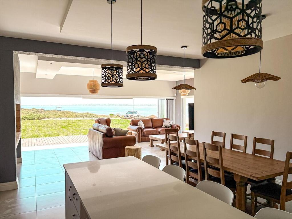 a kitchen and living room with a table and chairs at Slipway House Beachfront Villa in Britannia Bay