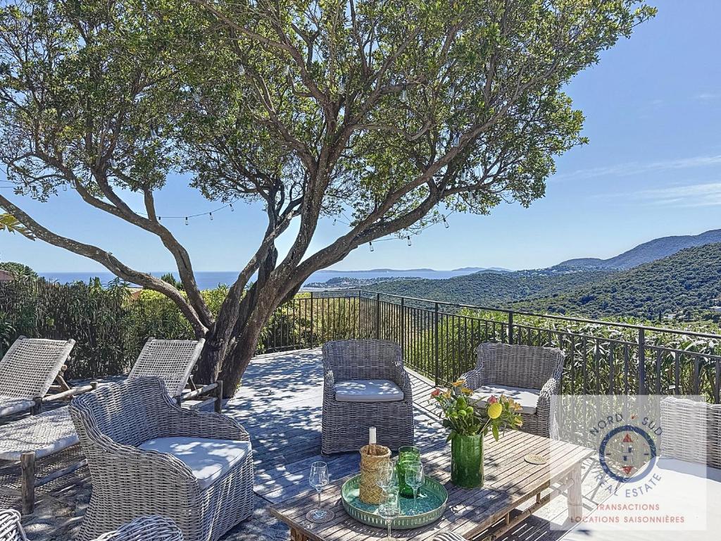 d'une terrasse avec une table, des chaises et un arbre. dans l'établissement Villa SHALIMAR vue mer et piscine chauffée, à La Croix-Valmer