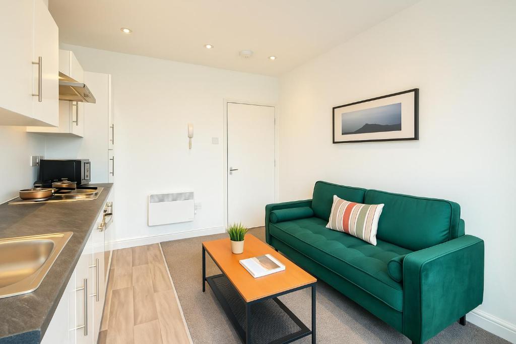 a living room with a green couch and a table at 2 Bedroom Apartment Near City Centre, Uni & Parks! in Cardiff