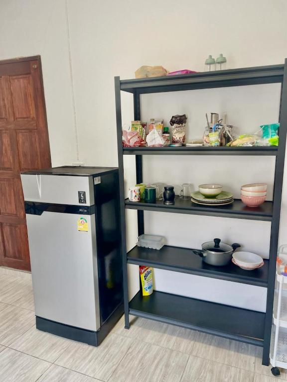 a kitchen with a refrigerator and a shelf with dishes at Unity coliving in Thong Sala