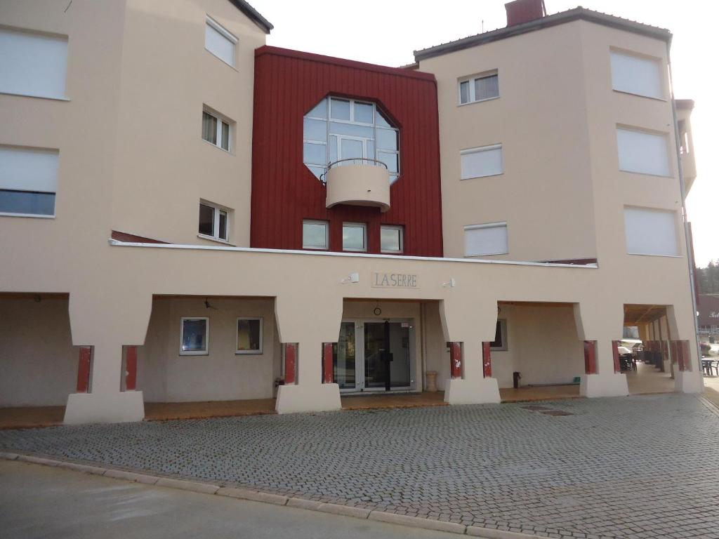 un immeuble d'appartements avec une façade rouge et blanche dans l'établissement La Serre - Centre du village - Départ des pistes de fond et Skibus à 50m, à Prémanon