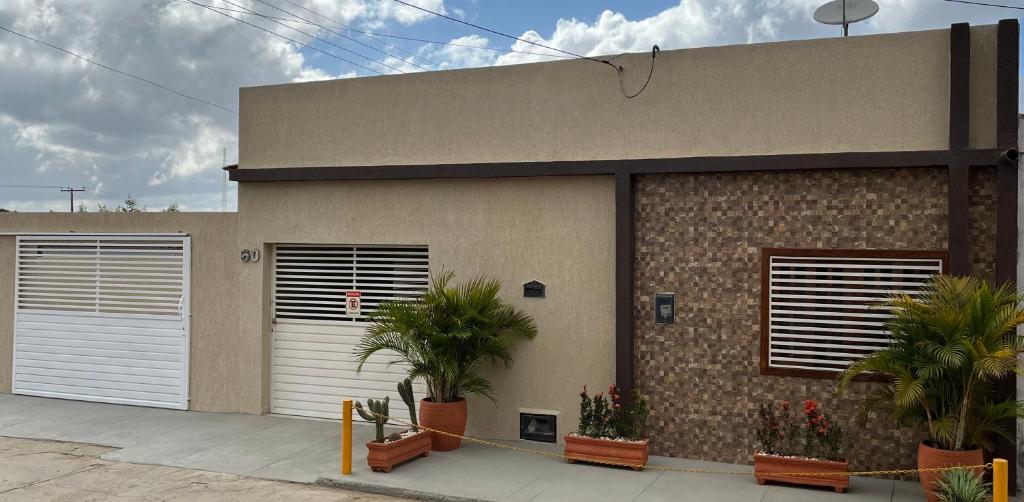 a building with two white garage doors and plants at Casa de temporada da vó zelina in Piranhas