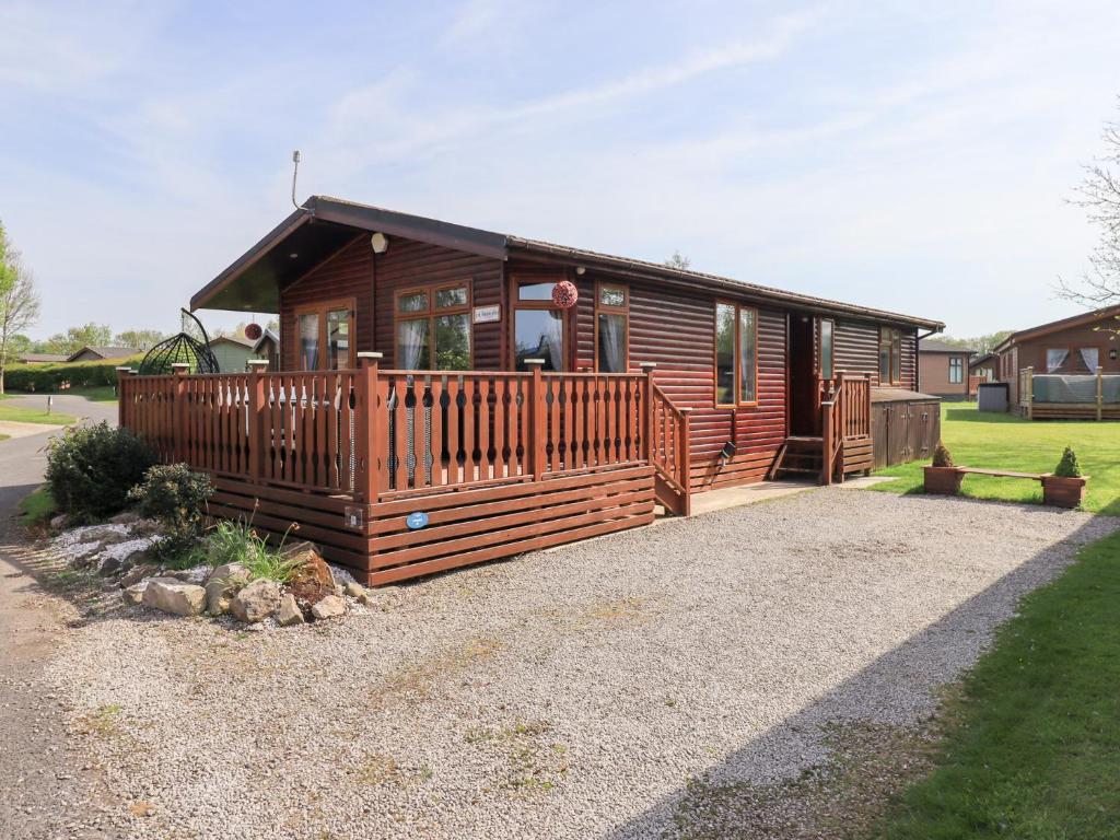 a large wooden cabin with a large deck at Our Happy Place in Carnforth