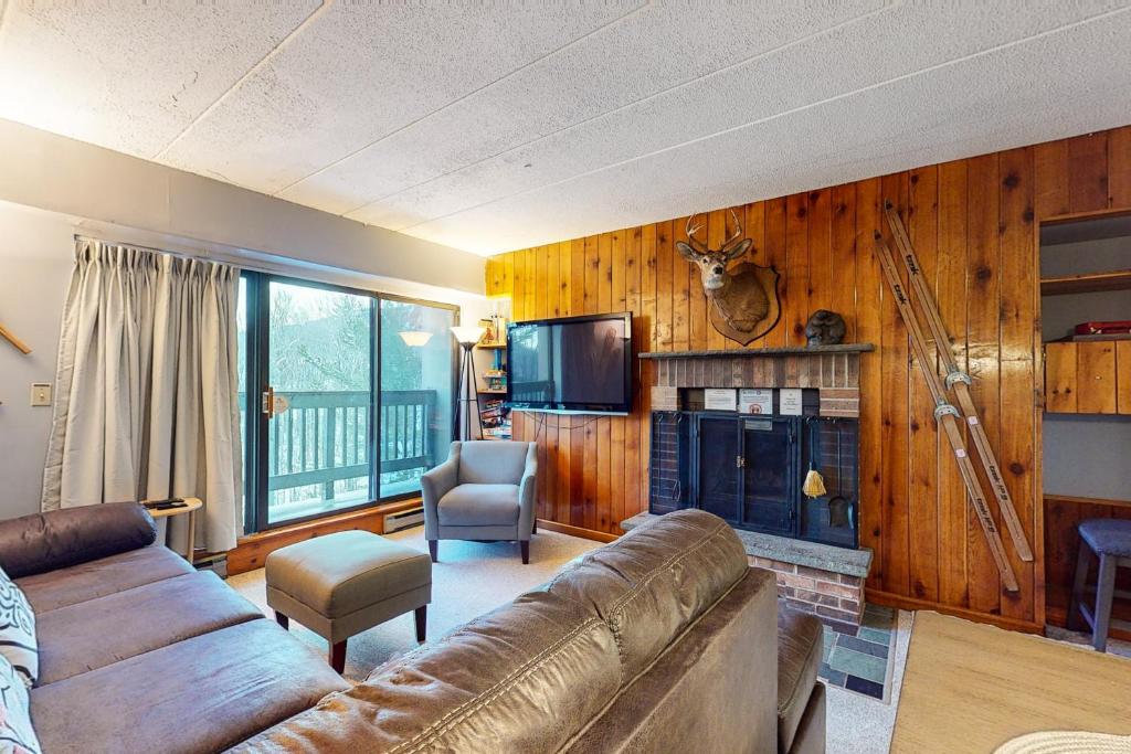 a living room with a leather couch and a television at Mountain Green - 2E3 in Killington