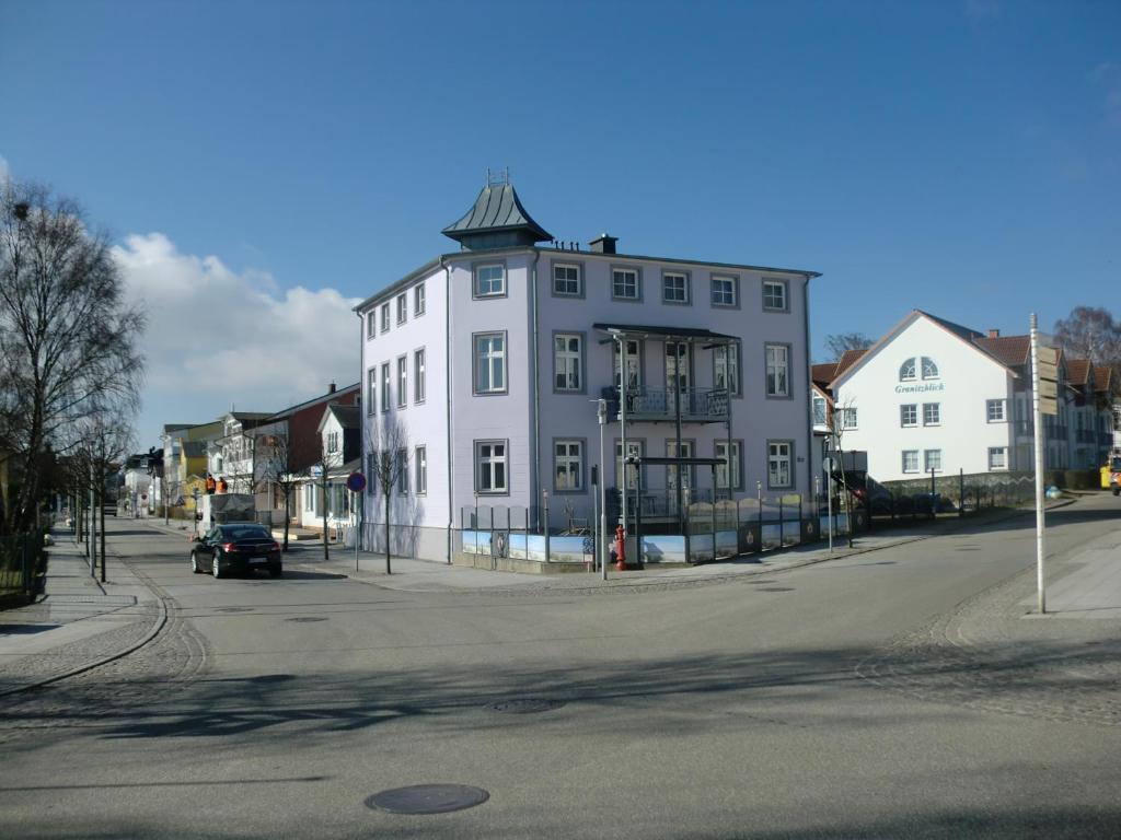 a large white building with a tower on a street at Pension Granitzeck in Ostseebad Sellin