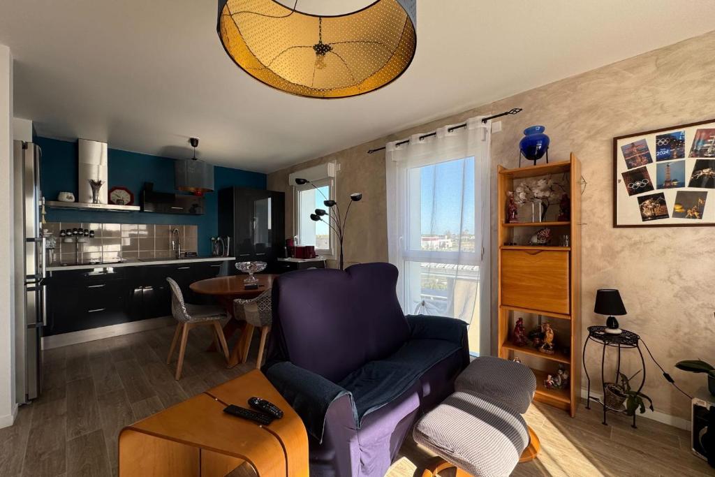 Il comprend un salon avec un canapé violet et une cuisine. dans l'établissement Apartment with balcony in Biéville-Beuville, à Biéville-Beuville