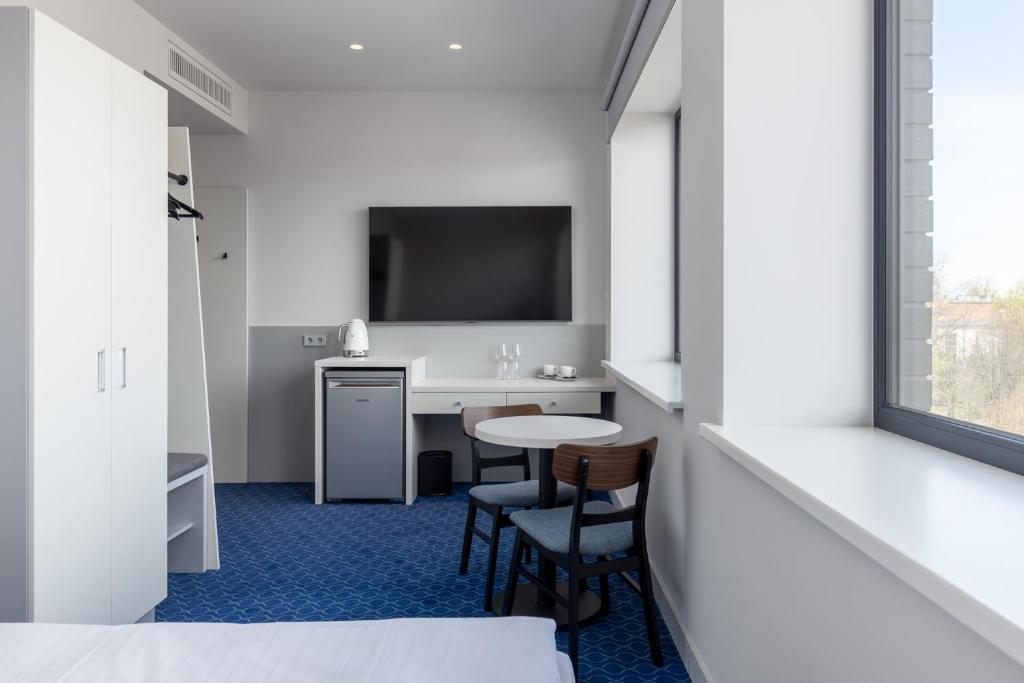Una habitación de hotel con escritorio y televisión. en Roze Kurmajas Hotel, en Liepāja