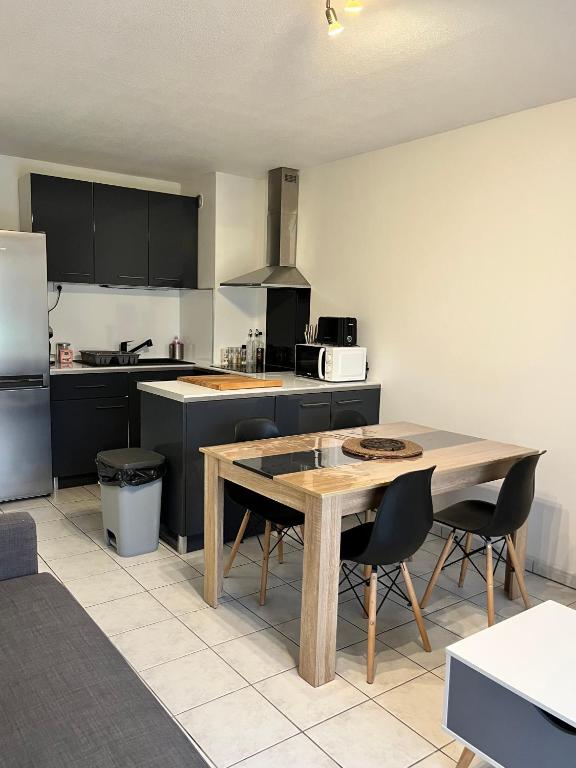 Il comprend une cuisine avec une table et des chaises en bois. dans l'établissement T2 avec jardinet à Aucamville, TOULOUSE, à Toulouse