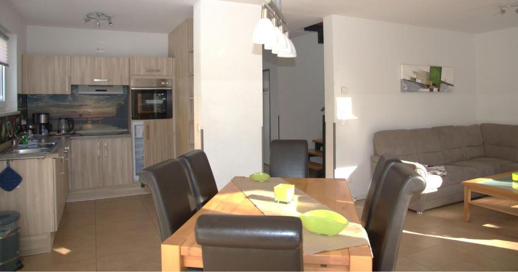 eine Küche und ein Wohnzimmer mit einem Tisch und einem Sofa in der Unterkunft Ferienpark Rübezahl am Müggelsee, Haus 21 Efeu mit eigener Sauna, idealer Ort für Natur- und Erholungssuchende, für Radfahrer, Familien mit Kindern und Hundeliebhaber in Berlin