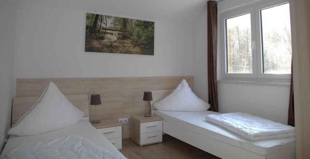 ein Schlafzimmer mit zwei weißen Betten und einem Fenster in der Unterkunft Ferienpark Rübezahl am Müggelsee, Haus 21 Efeu mit eigener Sauna, idealer Ort für Natur- und Erholungssuchende, für Radfahrer, Familien mit Kindern und Hundeliebhaber in Berlin