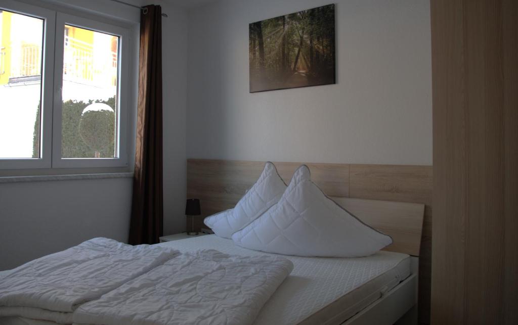 ein Schlafzimmer mit einem Bett mit weißen Laken und einem Fenster in der Unterkunft Ferienpark Rübezahl am Müggelsee, Haus 21 Efeu mit eigener Sauna, idealer Ort für Natur- und Erholungssuchende, für Radfahrer, Familien mit Kindern und Hundeliebhaber in Berlin