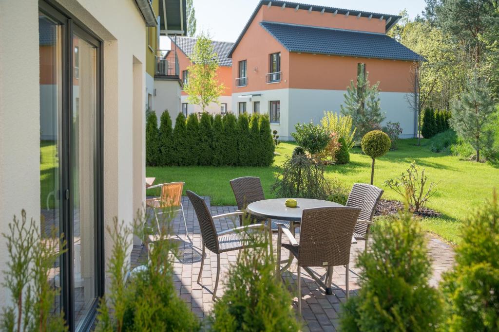 eine Terrasse mit Tisch und Stühlen in einem Hof in der Unterkunft Ferienpark Rübezahl am Müggelsee, Haus 21 Efeu mit eigener Sauna, idealer Ort für Natur- und Erholungssuchende, für Radfahrer, Familien mit Kindern und Hundeliebhaber in Berlin