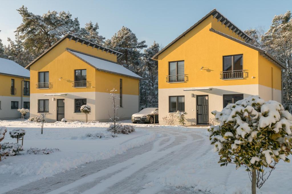 eine Reihe gelber Häuser im Schnee in der Unterkunft Ferienpark Rübezahl am Müggelsee, Haus 20 Mohn mit eigener Sauna, idealer Ort für Natur- und Erholungssuchende, für Radfahrer und Familien mit Kindern in Berlin