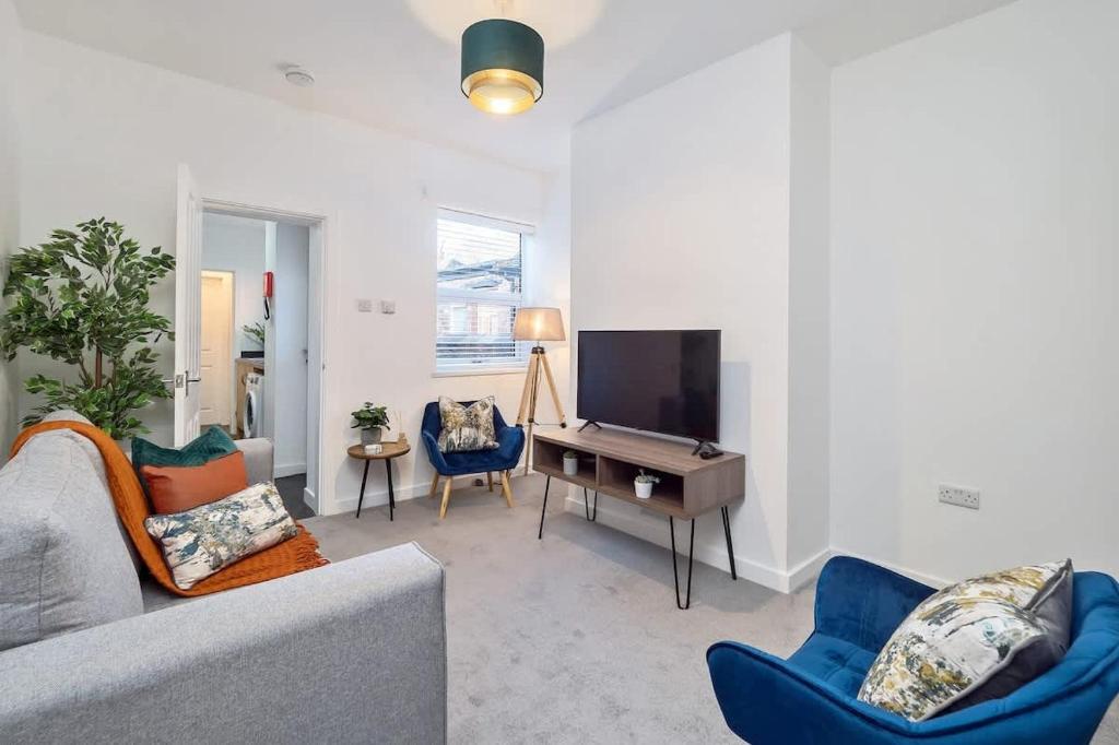 a living room with a couch and a desk and a tv at Nursery House by Truestays - 3 Bedroom House in Stoke-on-Trent in Stoke on Trent