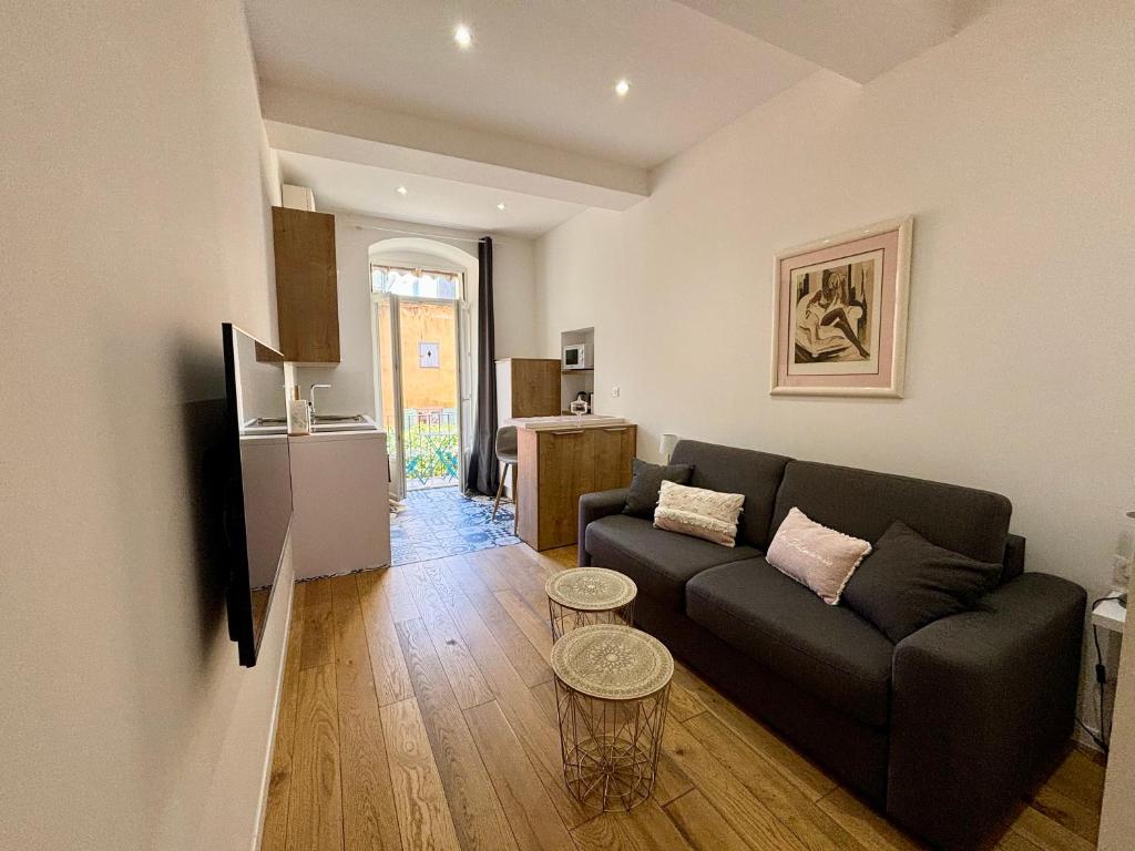 un salon avec un canapé noir et une cuisine dans l'établissement Casamea - Studio, Terrasse, Clim, Centre hist, à Ajaccio