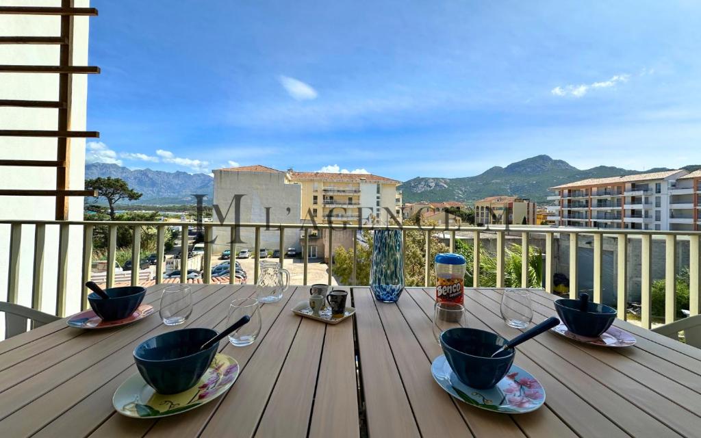 une table en bois avec des tasses et des cuillères sur un balcon dans l'établissement Appartement Colomba, à Calvi