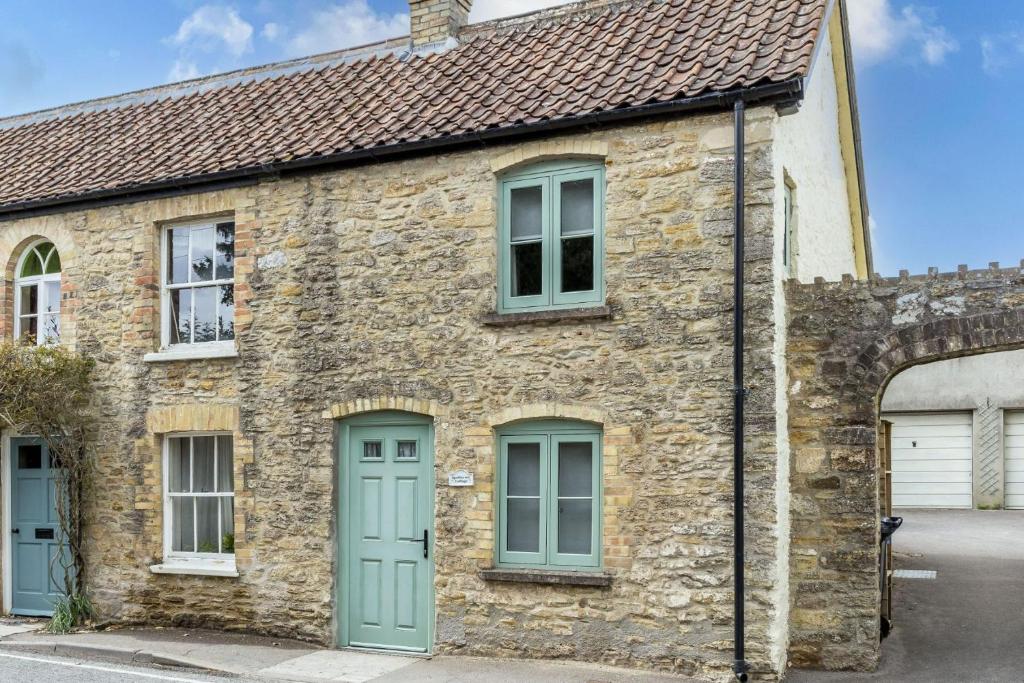 an old stone house with a green door at Apothecary Cottage - Pet Friendly Wedmore Couples Cottage - Free WiFi - Free Parking in Wedmore