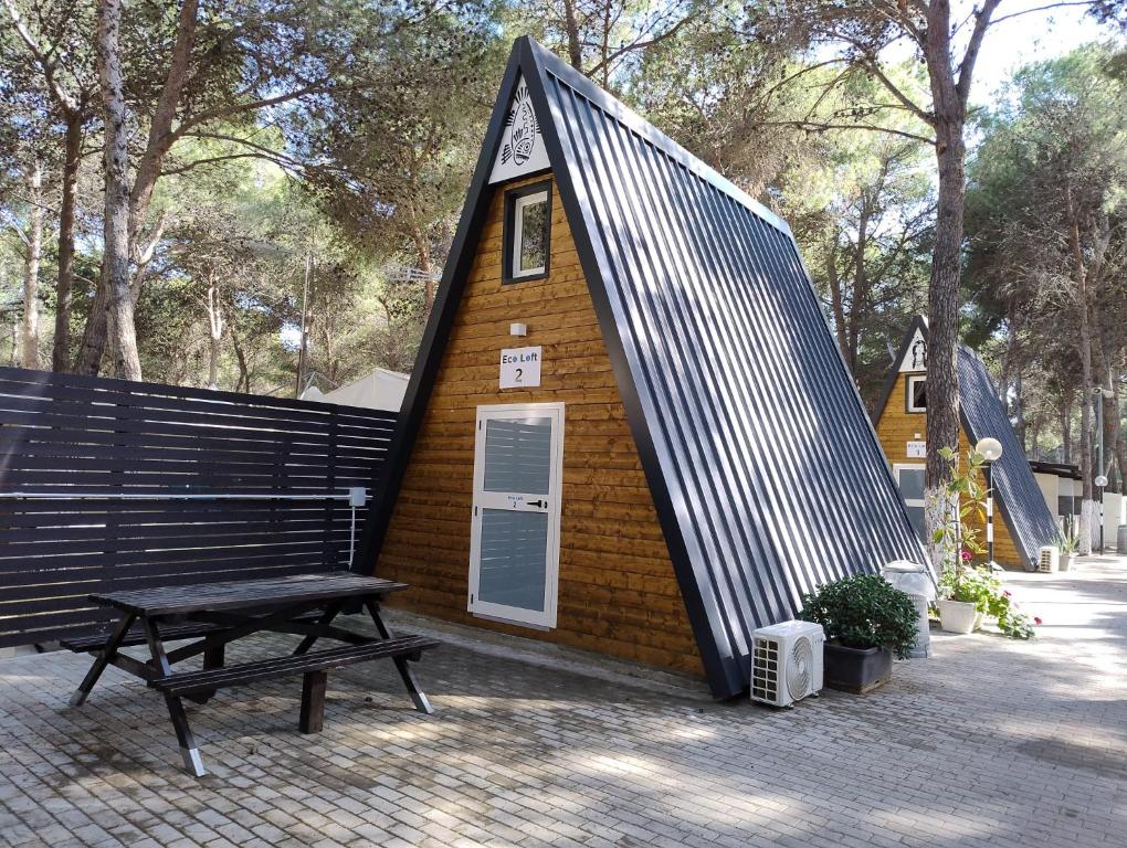 ein kleines Haus mit einer Bank und einem Picknicktisch in der Unterkunft Glamping Policoro Village in Policoro