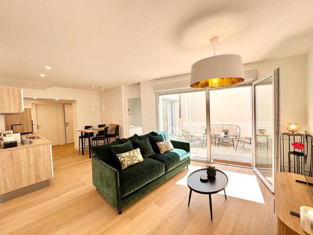 un salon avec un canapé vert et une table dans l'établissement Patio Signature - Cœur de Reims, à Reims