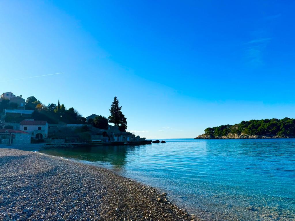 une plage d'eau bleue et des maisons sur la côte dans l'établissement Green Sea Villa - Wild Orange Dubrovnik, à Zaton