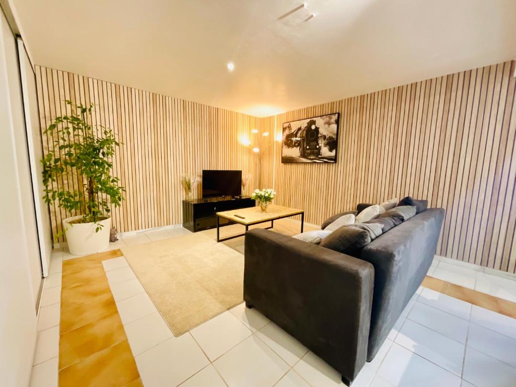 a living room with a black leather couch and a table at Appartement avec piscine et barbecue in La Farlède