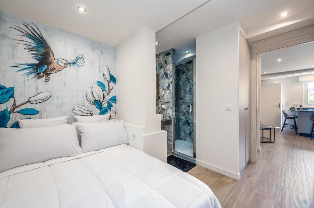 une chambre avec un grand lit blanc avec une fresque de paon dans l'établissement Cannes - T3 Neuf - Clim, plages et centre à pied - Ness House, à Cannes