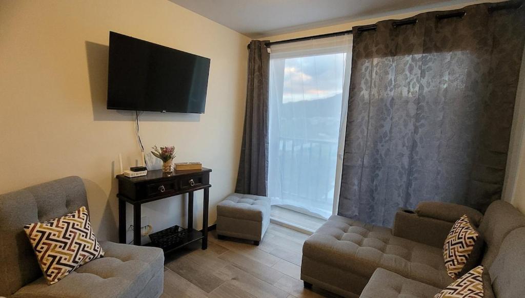a living room with a couch and a large window at Take a rest nearest to Antigua Guatemala in Santa Lucía Milpas Altas
