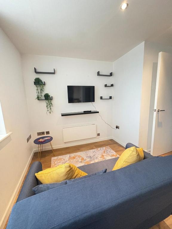 a living room with a blue couch and a tv at Cosy Flat Leeds City Centre in Central Station