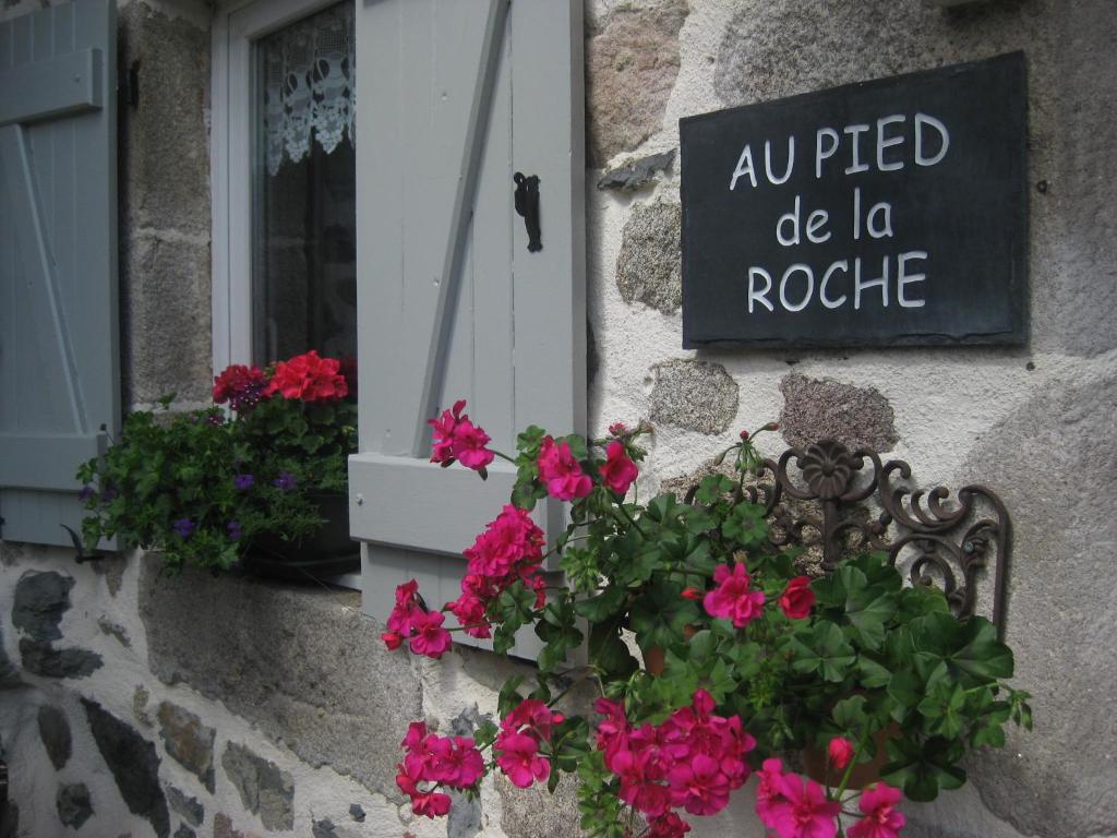 una ventana con una maceta de flores y una señal en Au Pied de la Roche, en Roche-en-Régnier