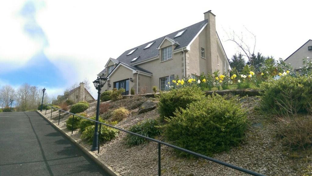a house on the side of a hill with flowers at Woodview Bed & Breakfast. in Letterkenny
