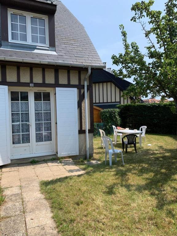 une maison avec une table et des chaises dans la cour dans l'établissement Cottage Normand avec jardin de 80 m2, à Villers-sur-Mer