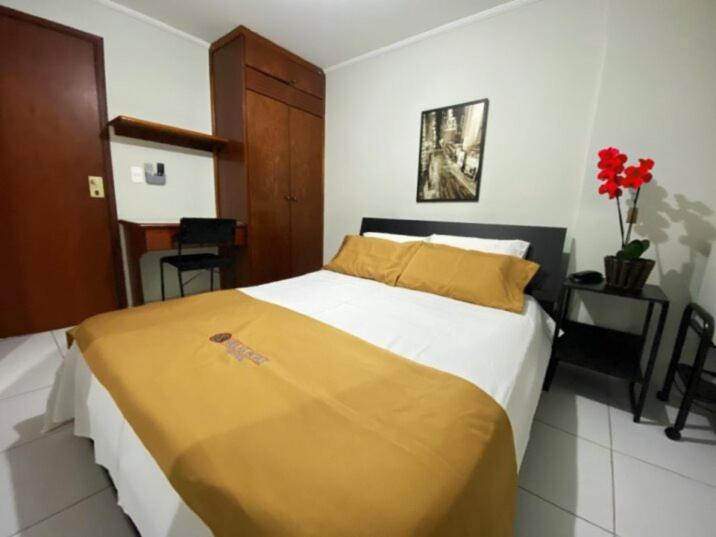 a bedroom with a large bed with a yellow blanket at Villas Boas Hotel in Campinas