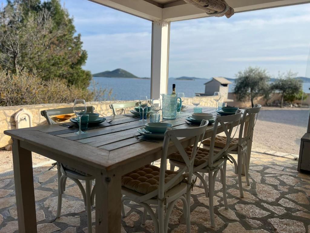 Una mesa y sillas de madera en un patio con vista al mar. en Adriatic Dream - Mobile Home - Oaza Mira, en Drage