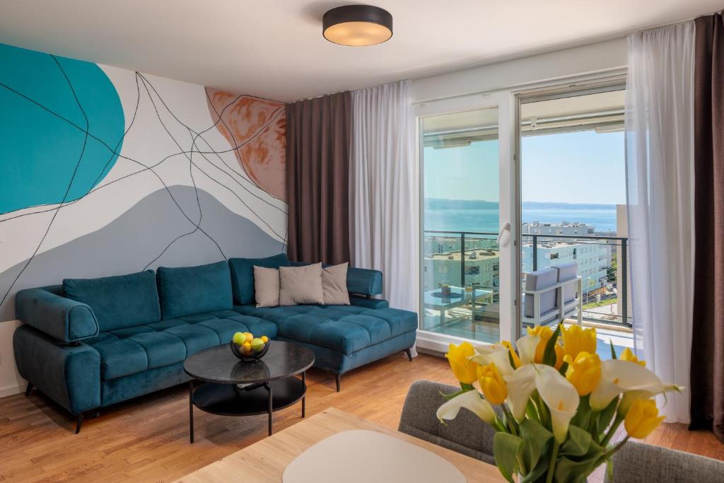a living room with a blue couch and a large window at Split For You - 2BR Apartment with Free Garage Parking in Split