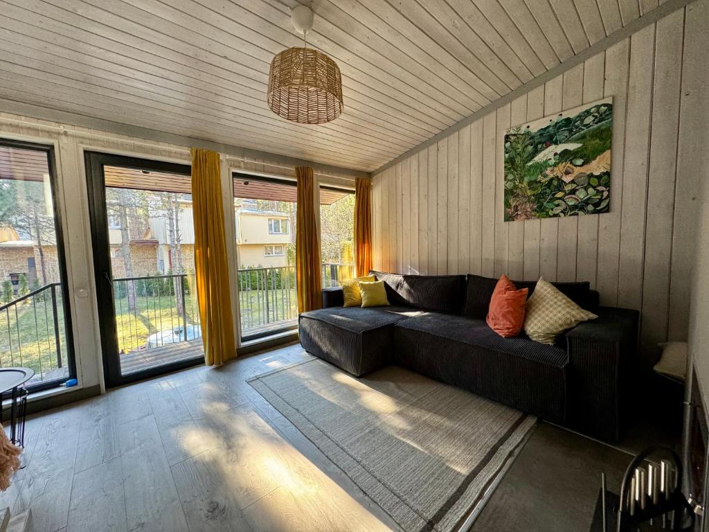 a living room with a black couch and windows at Sunny family holiday home in Jurmala in Jūrmala