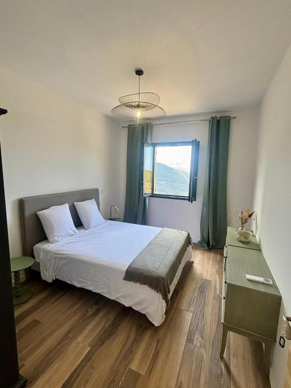 une chambre avec un grand lit et une fenêtre dans l'établissement Les chambres du Cap Corse, à Barrettali