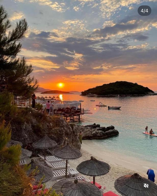 a sunset on a beach with umbrellas on the beach at Guest House Moonlight in Ksamil