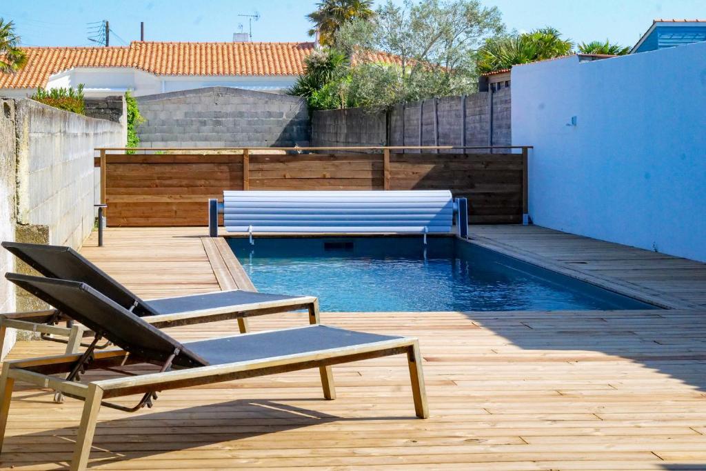 une piscine avec deux chaises et un banc sur une terrasse dans l'établissement Très jolie maison - Piscine & Jacuzzi - Les Sables - 9 personnes, à Les Sables-dʼOlonne