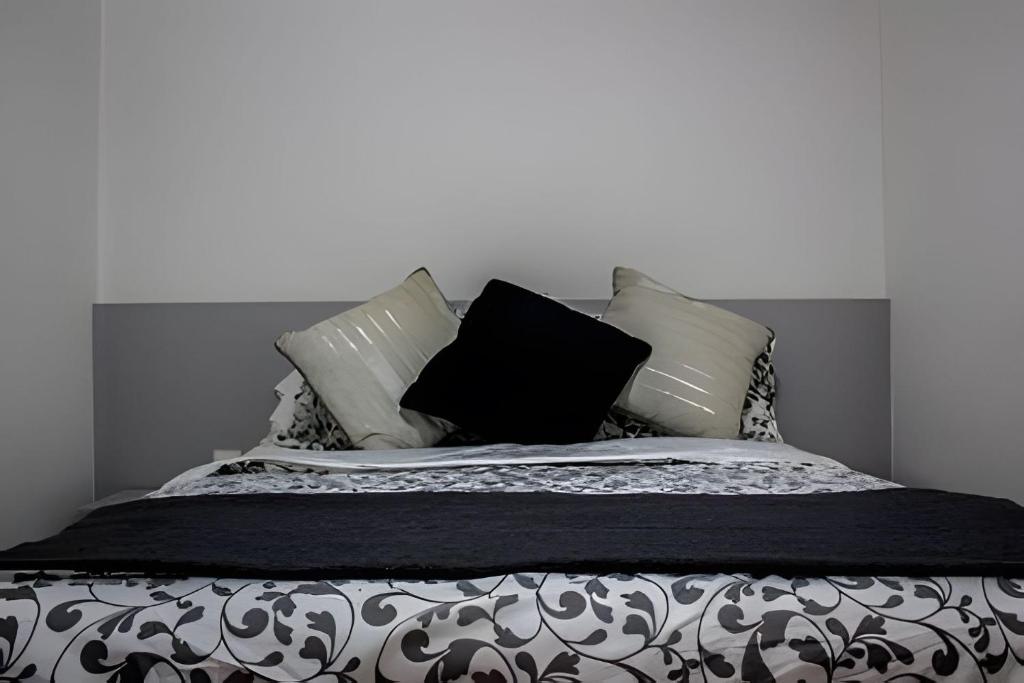 a bed with black and white pillows on it at 4let BH Del Rey in Belo Horizonte