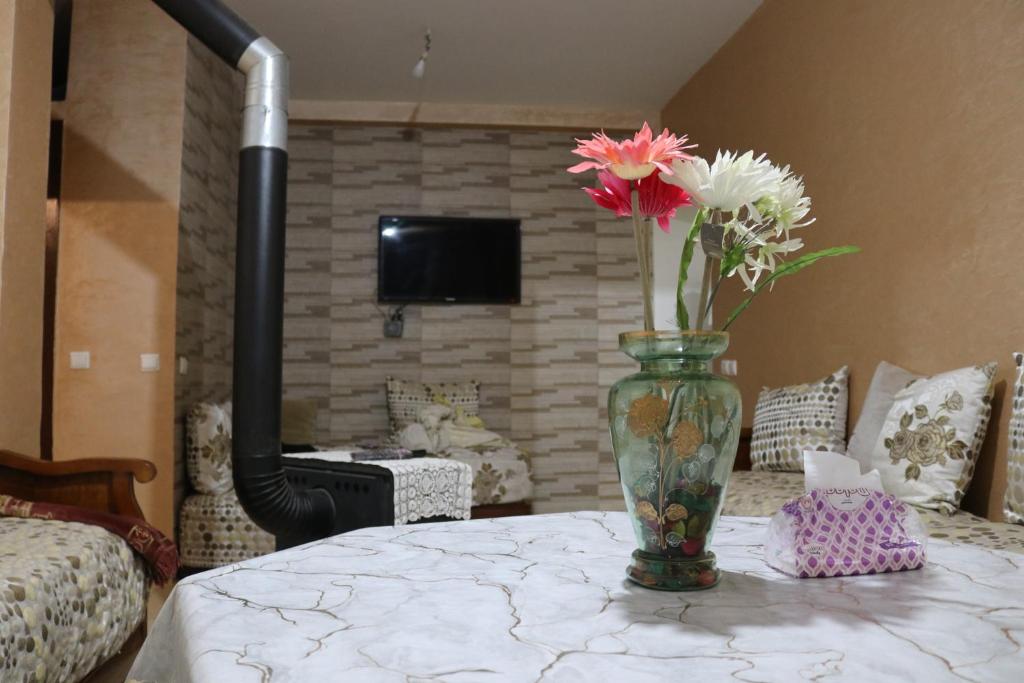 eine Vase mit Blumen auf einem Tisch in einem Zimmer in der Unterkunft Appartement juste pour les familles in Ifrane