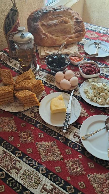 een tafel met borden eten en brood bij Manan Guesthouse in Chʼkalovka