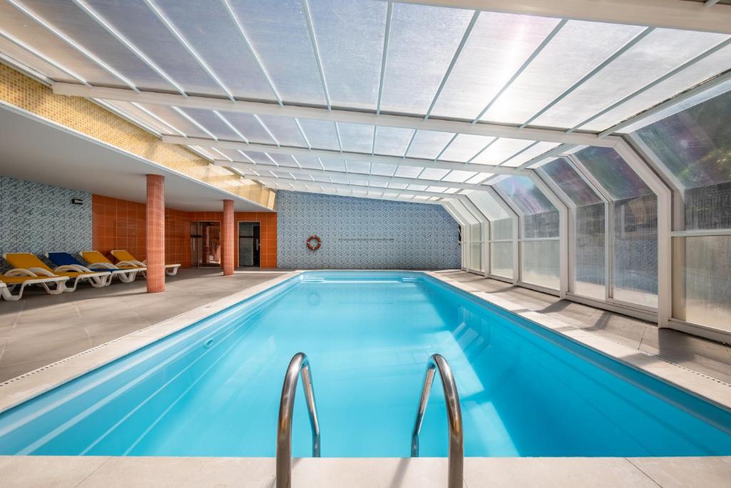 a large swimming pool with a large ceiling and windows at Hotel Colmeia in Monte Real