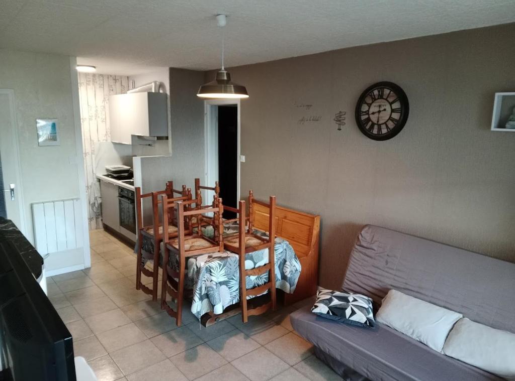 un salon avec un canapé et une horloge au mur dans l'établissement Saint Hilaire de Riez appartement T2 a 200m mer, à La Celle-sous-Gouzon
