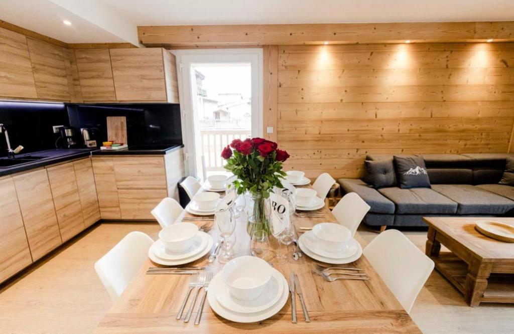 une salle à manger dotée d'une table avec des assiettes et des fleurs. dans l'établissement La Plane - Les Tanières de Montgenèvre - Appartement 8p front de neige, à Montgenèvre