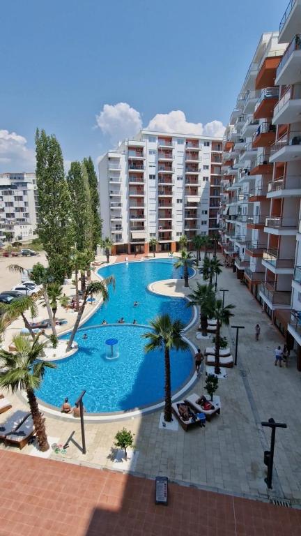 a large swimming pool with palm trees and buildings at AURORA Apartment Shëngjin Kune in Shëngjin
